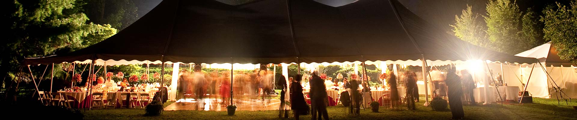Outdoor wedding celebration under a tent. People dancing and eating