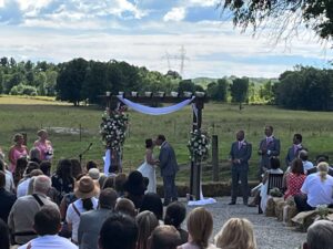 The Bride and Groom exchange vows under a floral arch at the farm