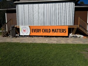 Shoes under a banner reading Every Child Matters is another reminder of the grief of this community