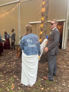 The bride wears a jean jacket with Mrs Adams on the back
