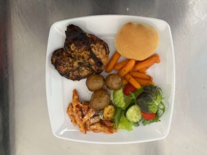 Plate of maple bbq chicken breasts, maple glazed baby carrots, roasted baby potatoes, mixed garden salad and hot vegetarian pasta from Shaws Catering custom bbq buffet