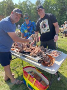 Three men pictured over a well eaten roast pig from Shaws DIY pig roast