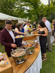 Guests enjoy a delicious meal of roast pig, bbq chicken, Caesar Salad, macaroni and cheese and fresh corn on the cob. A perfect summer meal!